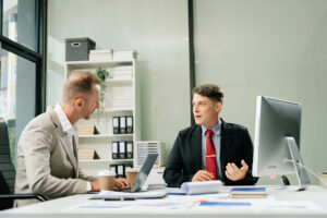 NCR service company representative reviewing ATM service history with a bank manager at a desk
